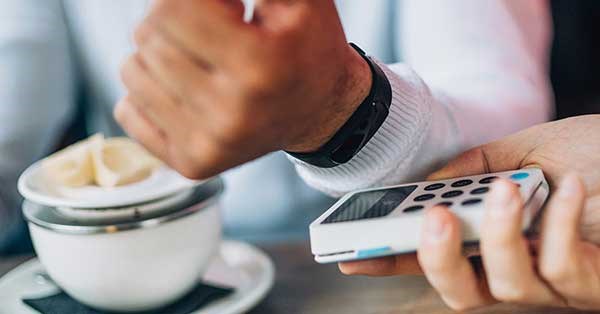 Mann betaler med FitBit-Pay på café, til iillustrasjon for smartklokker