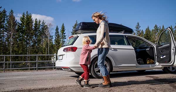Mor og barn danser foran bilen i vårsola, illustrasjon til hvordan finansiere bilkjøpet