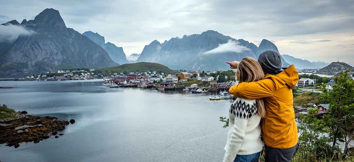 Kvinne og mann i turklær nyter utsikt over lofoten, til illustrasjon for sparekalkulator