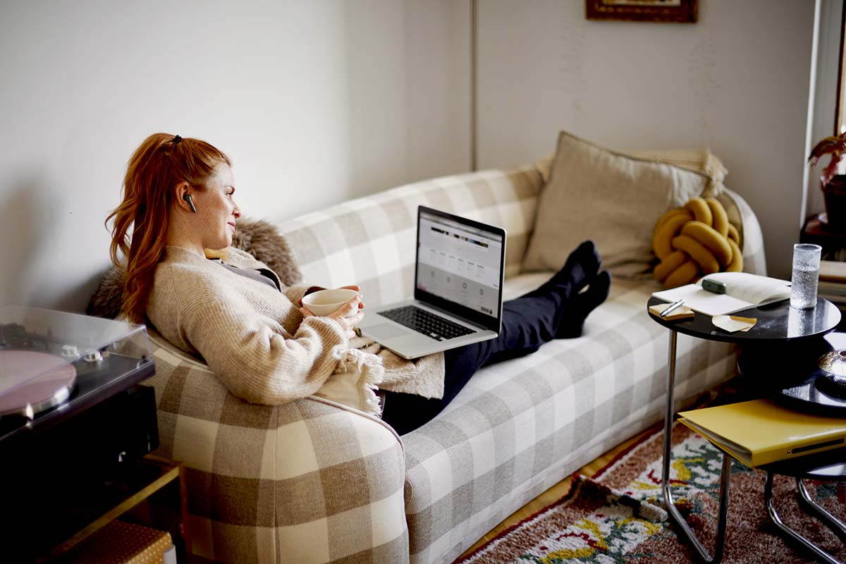 jente sitter i sofaen og ser på pc - illustrasjon til trygg kortbruk