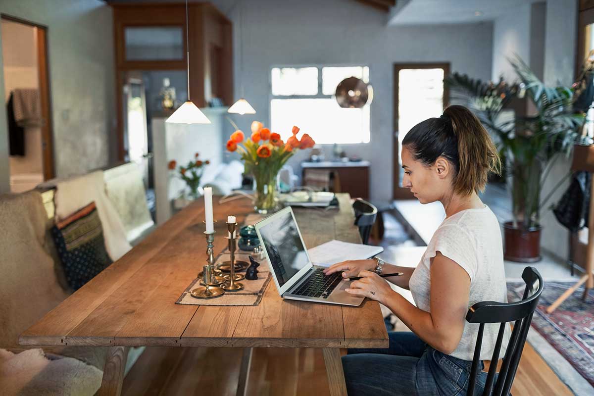 Kvinne sitter på kjøkkenbordet og forbereder seg til å kjøpe bolig