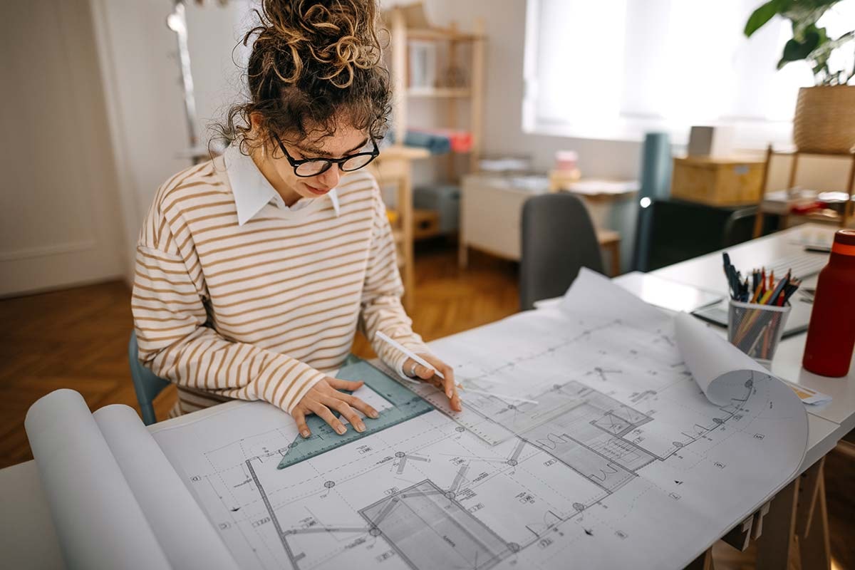 Arkitekt jobber med tegninger for noen som skal bygge på huset