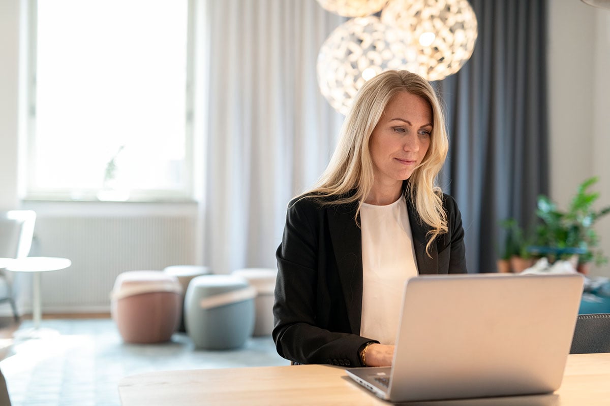 Dame sitter ved en pult og jobber på en laptop, til illustrasjon for hvor mye kan jeg kjøpe bolig for