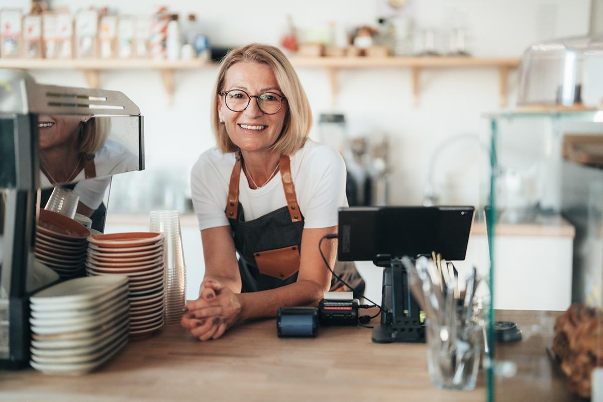 Dame bak disken i kafeen sin, til illustrasjon for hva du bør tenke på når du velger bank til din bedrift