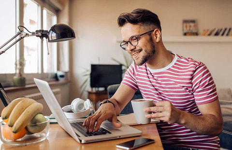 Mann drikker kaffe og ser på pc, illustrasjon til boligsparing