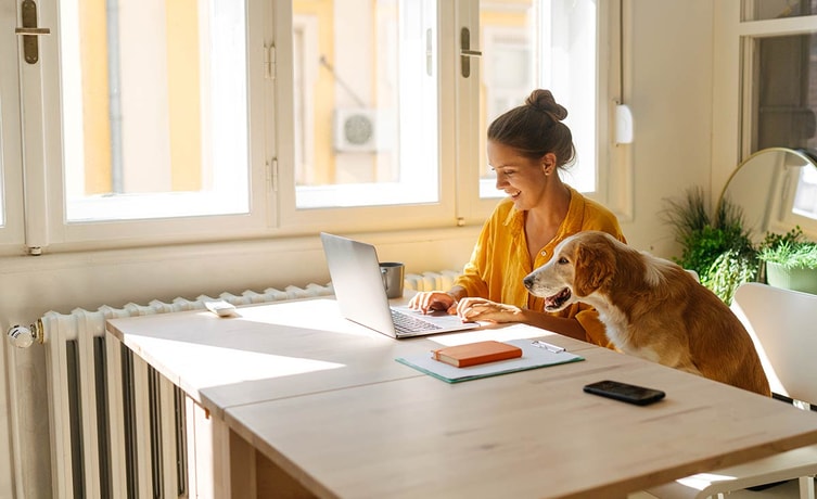Dame og hund sitter ved spisebord og ser på laptop, til illustrasjon for BankID