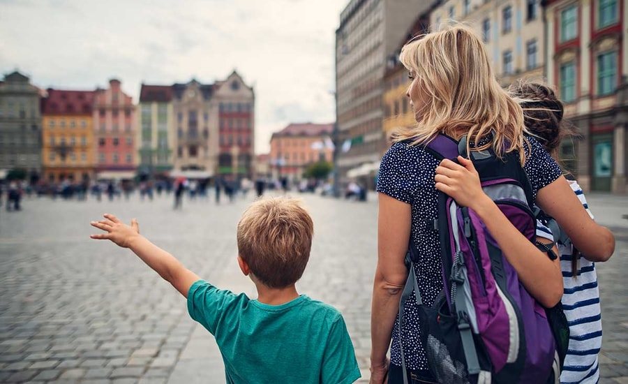 En kvinne og to barn går sammen i sentrum av en by, til illustrasjon for kort