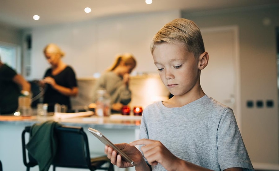 Gutt ser på mobiltelefonen sin, til illustrasjon for mine kort appen til barn