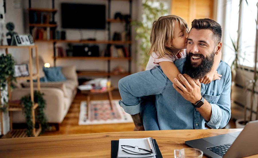 Mann sitter og jobber med et barn som klatrer på ryggen, til illustrasjon for fastrentelån