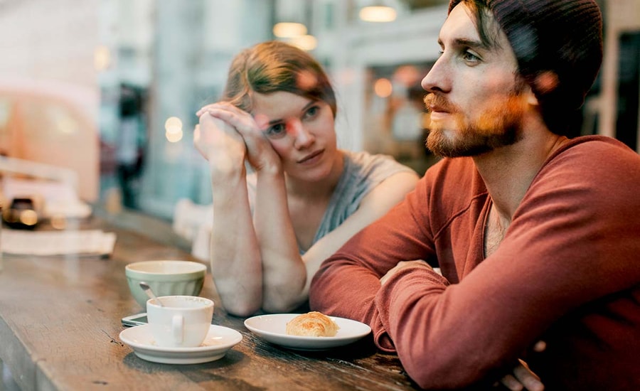 Kvinne og mann sitter på kafé, til illustrasjon for gjeld og parforhold