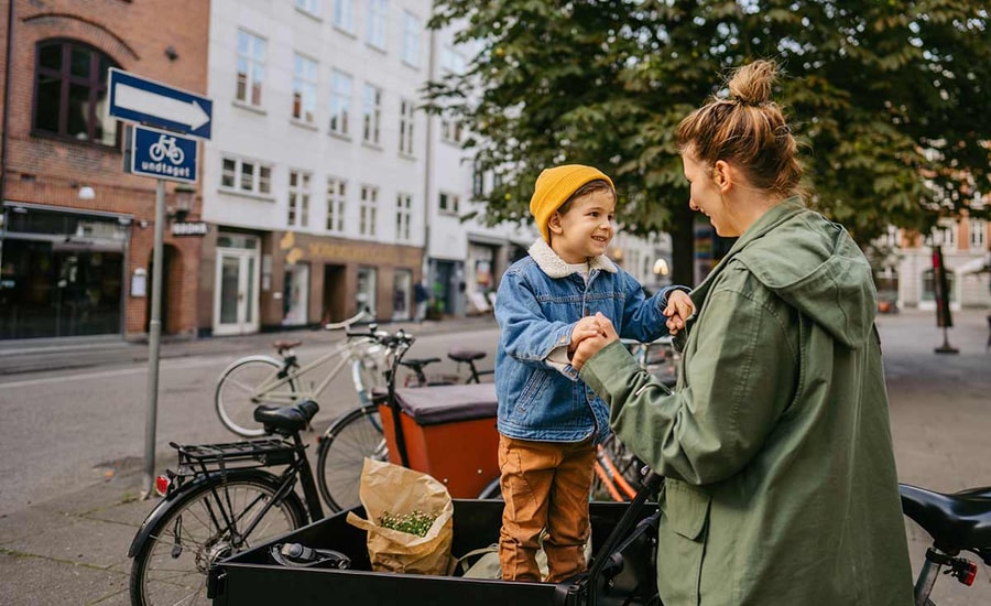 Mor og sønn holder hender mens gutten står på sykkelen, til illustrasjon for spareavtale