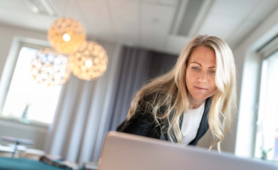 Kvinne med blazer lener seg over en datamaskin, til illustrasjon for finansavtaleloven