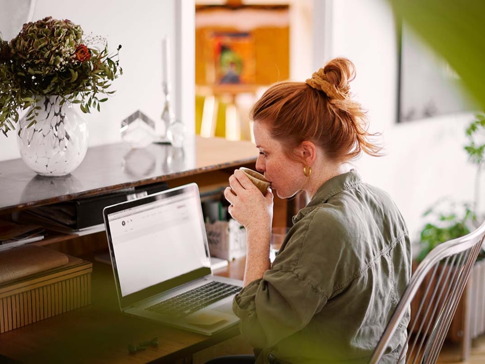 Dame sitter ved kontorpult og jobber på en PC, til illustrasjon for betale til utland