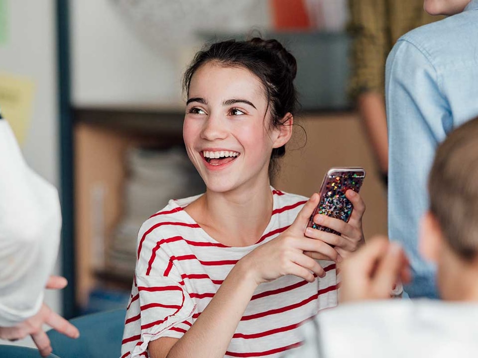 Ung jente holder en mobiltelefon, til illustrasjon for BankID for ungdom