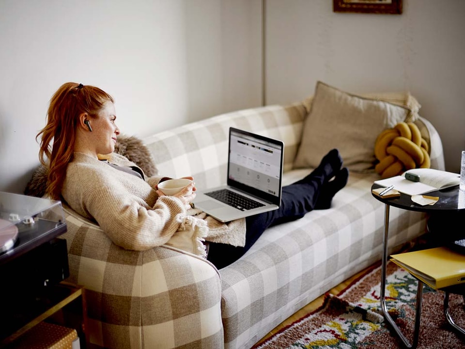 jente sitter i sofaen og ser på pc - illustrasjon til trygg kortbruk