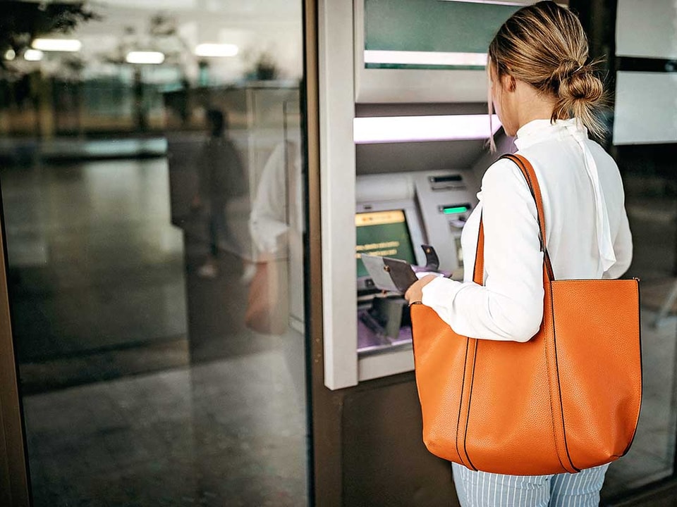 Dame tar ut penger i minibank - illustrasjon for lokal valuta