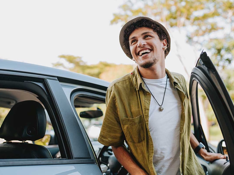 Mann smiler mens han går ut fra en bil, til illustrasjon for billån