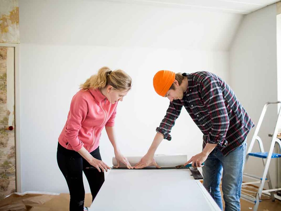 Dame og mann måler tapet mens de pusser opp, til illustrasjon for spare eller låne til oppussing