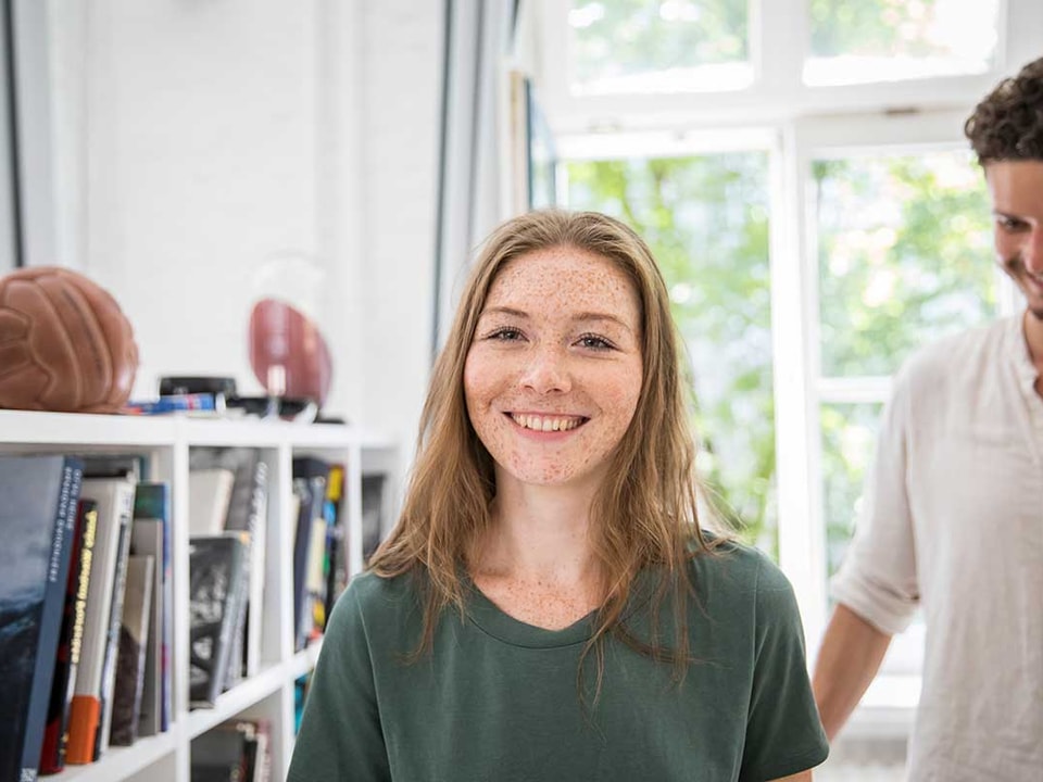 Jente står i leilighet og smiler mens en mann er bak henne, til illustrasjon for medlåntaker