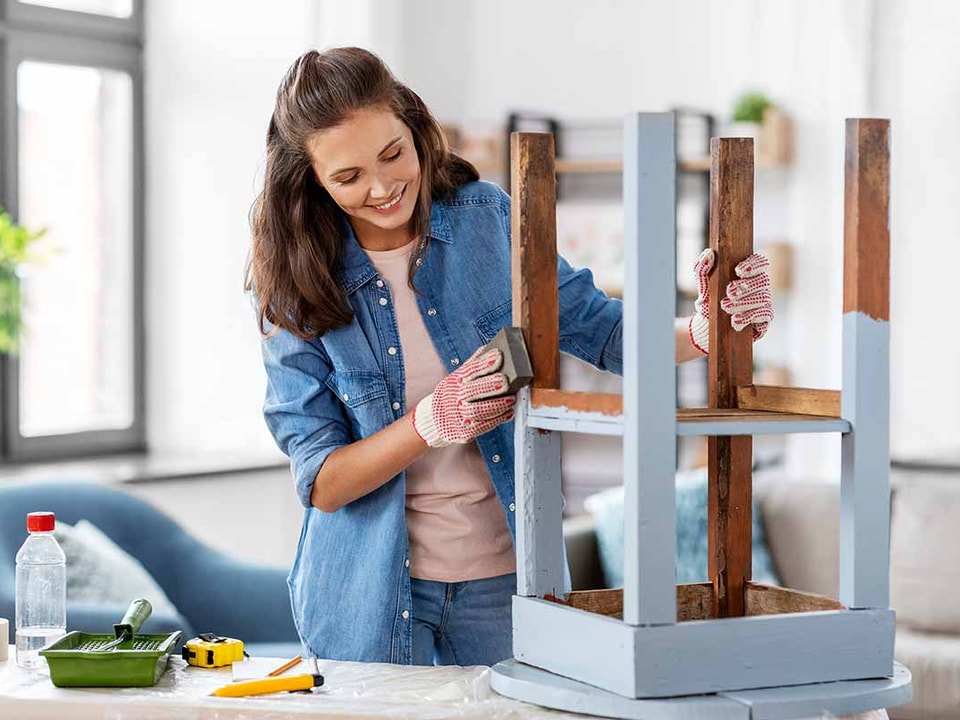 Dame pusser opp gammel krakk, til illustrasjon for miljøvennlig oppussing