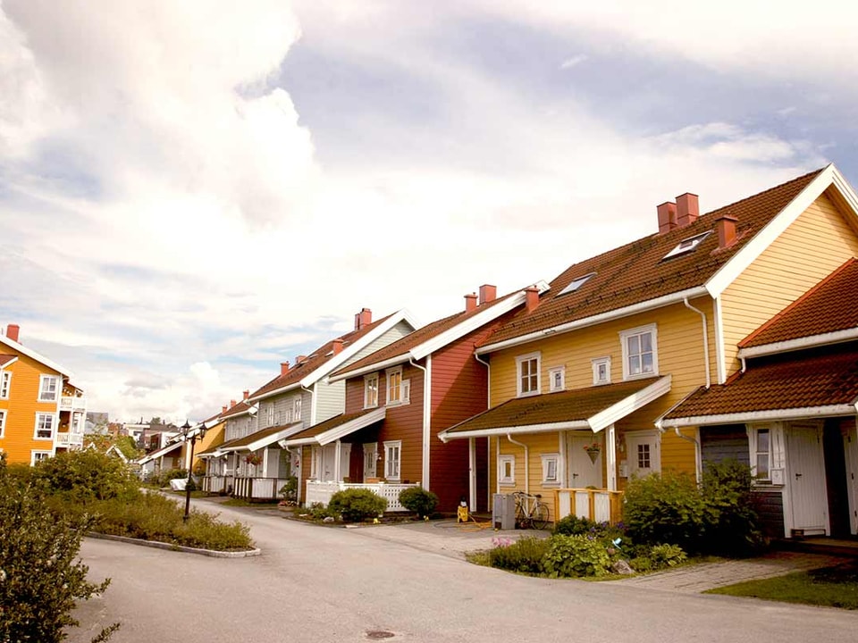 Flere hus i gul, grå og rød farge i en gate, til illustrasjon for skifte kledning og tak