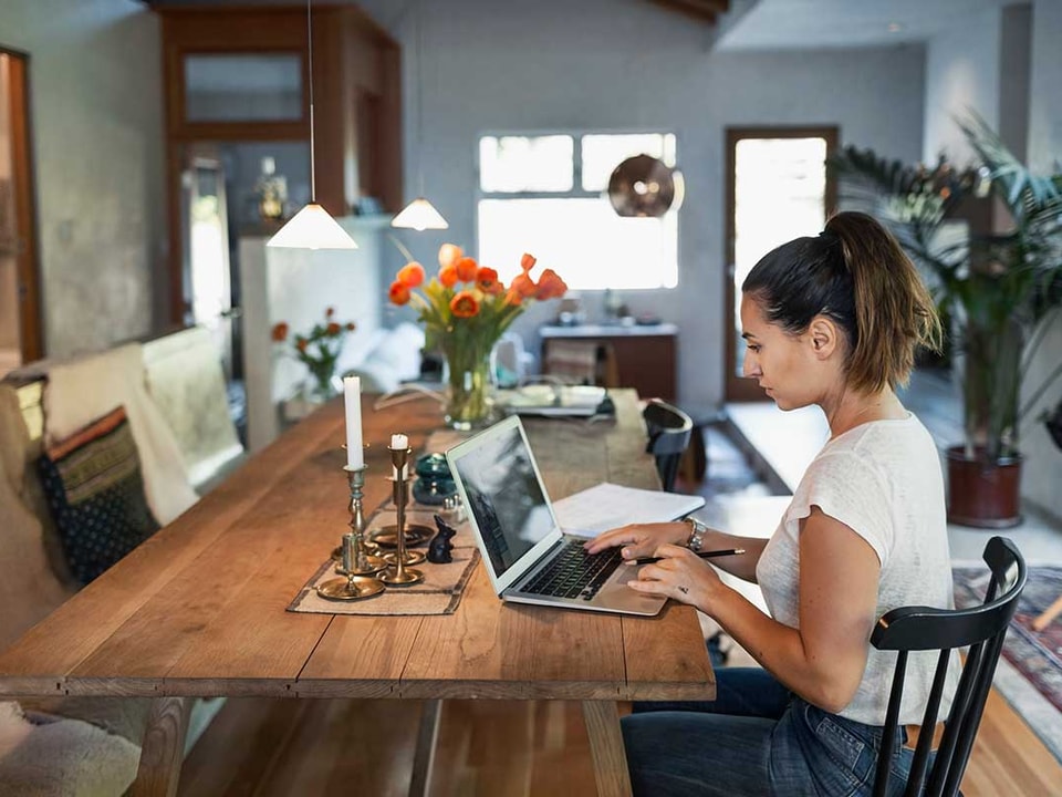 Kvinne sitter på kjøkkenbordet og forbereder seg til å kjøpe bolig