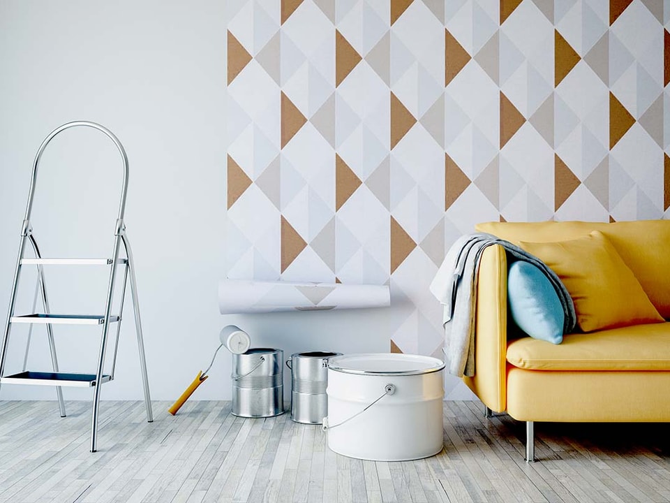 Gul sofa med tapet på veggen og malespann på gulvet, til illustrasjon for å øke boliglån for oppussing