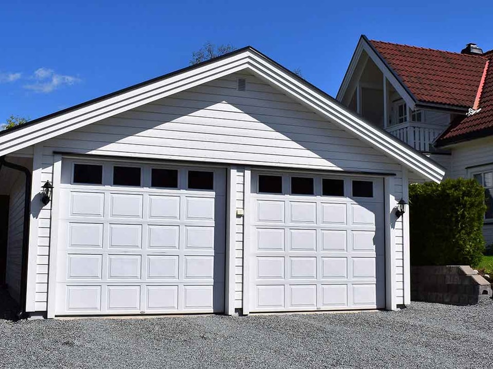 Dobbeltgarasje fremfor hvitt hus, til illustrasjon for bygge garasje