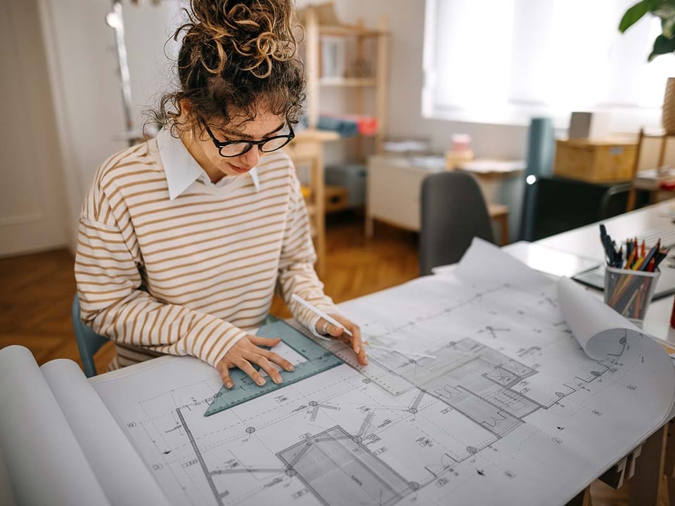 Arkitekt jobber med tegninger for noen som skal bygge på huset