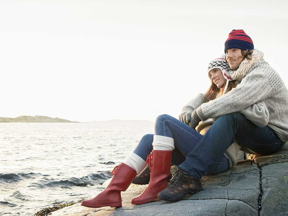 Kvinne lener seg mot mann på svaberg, til illustrasjon for skatt og samboere