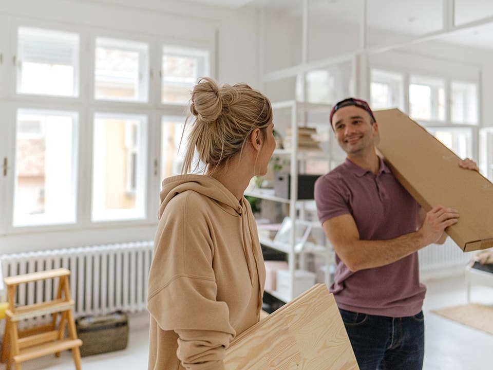 Kvinne og mann holder på esker mens de flytter inn i bolig, til illustrasjon for Finit Deleie