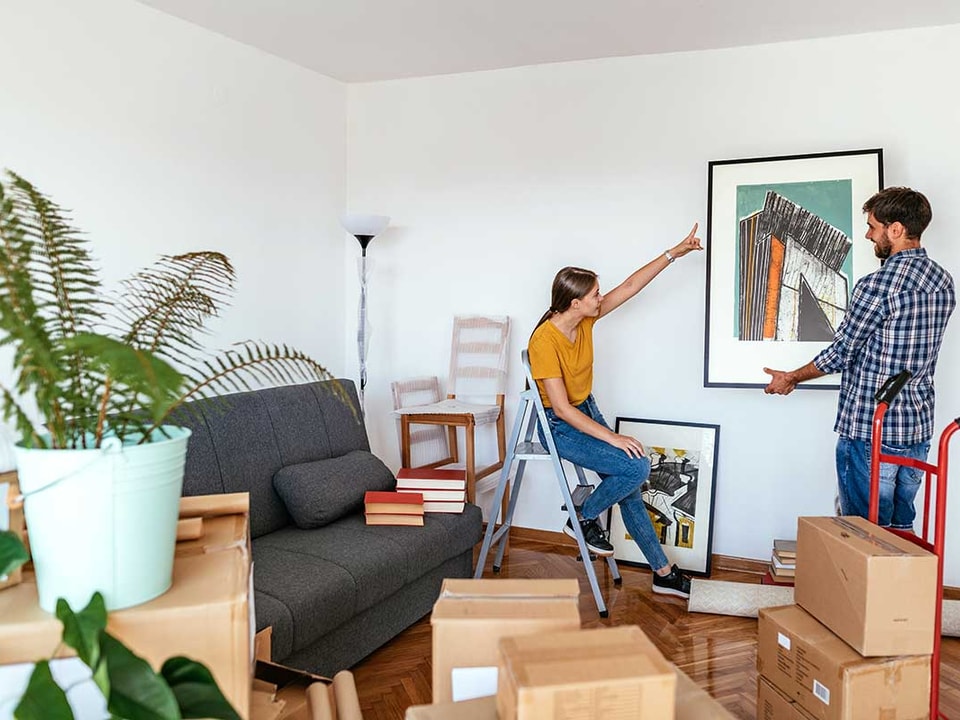 Ungt par har kjøpt bolig sammen og henger opp bilder, illustrasjon til  kjøpe bolig