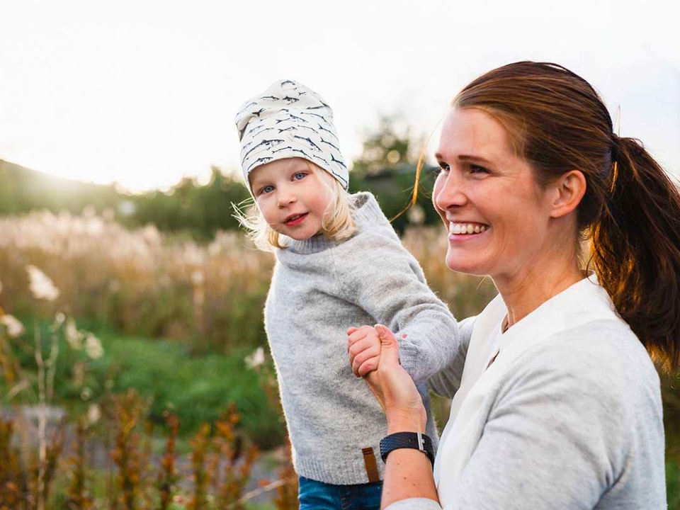 Kvinne og barn leker ute i gresset, til illustrasjon for budsjett til familie