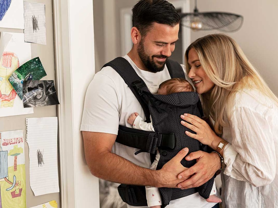 Mor og far med baby i bæresele, til illustrasjon for personlig økonomi