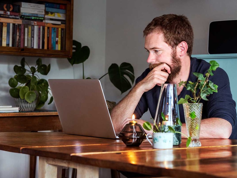 Mann ser tenkende på laptop - illustrasjon for pensjon