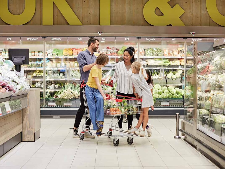 Mann, kvinne og to barn i en matbutikk, til illustrasjon for hvordan spare penger i hverdagen