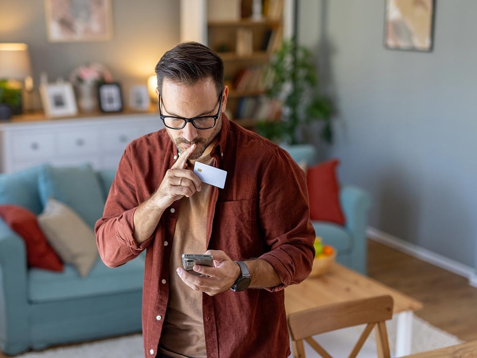 Mann ser mistenksom på mobiltelefonen og lurer på om det er fakturasvindel