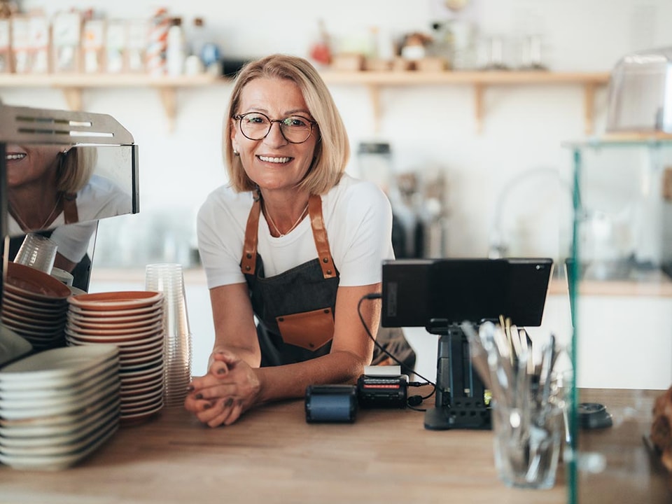 Dame bak disken i kafeen sin, til illustrasjon for hva du bør tenke på når du velger bank til din bedrift