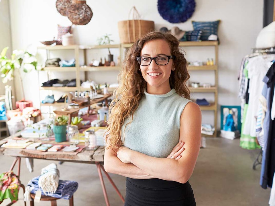 Dame står med armene i kors og viser frem sin butikk, til illustrasjon for selskap under stiftelse