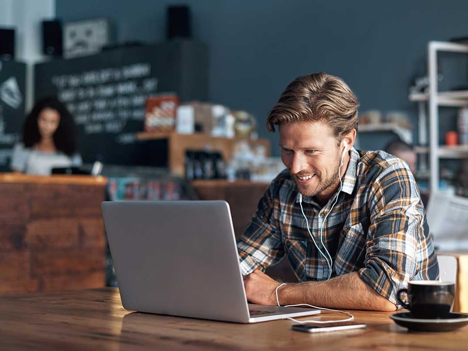 Mann med laptop på cafe