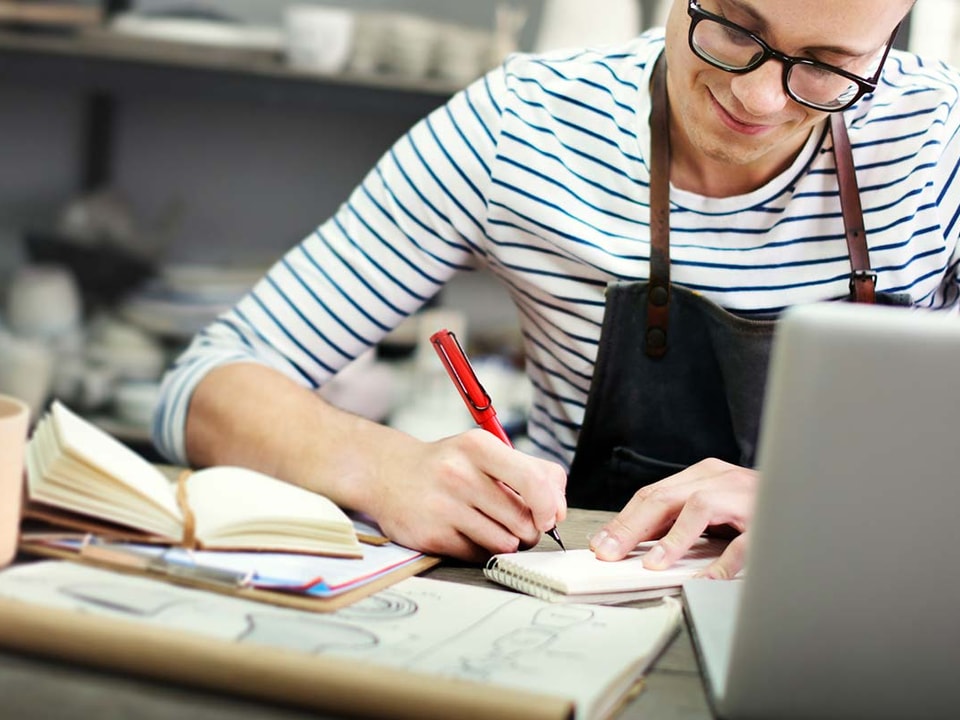 En mann med briller jobber på en laptop, fokusert på arbeid relatert til skattetrekkskonto