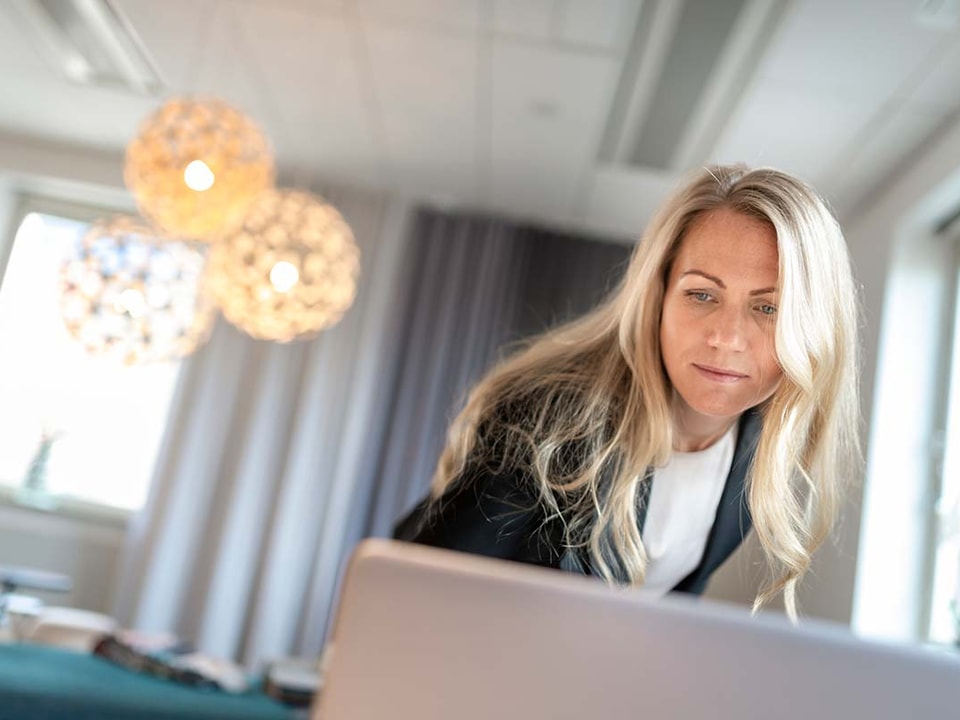 Mann sitter å plotter inn tall på nettbrettet, til illustrasjon for sparing til bedrift