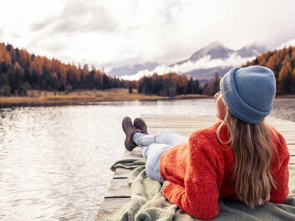 Jente ligger på brygga og ser utover høstlamdskap, illustrasjon til FNs bærekraftsmål