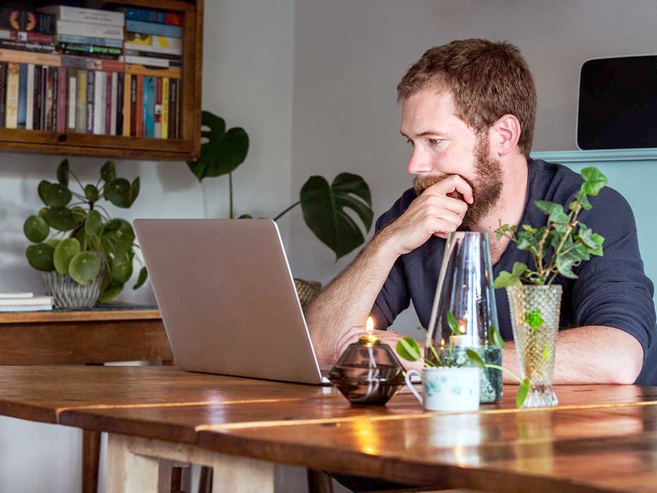Mann sitter med laptop, til illustrasjon for nettsikkerhet og kortbruk
