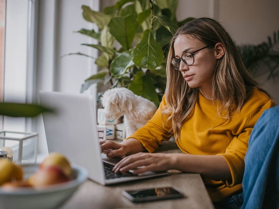 Kvinne sitter med laptop og jobber, til illustrasjon for å unngå skattesmell
