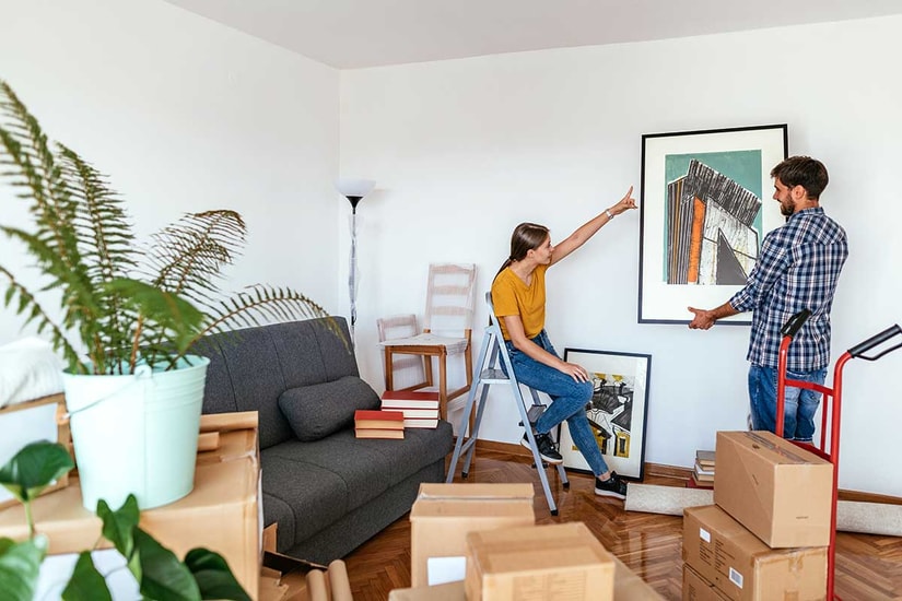 Jente peker på hvor gutten skal henge opp et bilde i deres nye bolig, til illustrasjon for kjøpe bolig