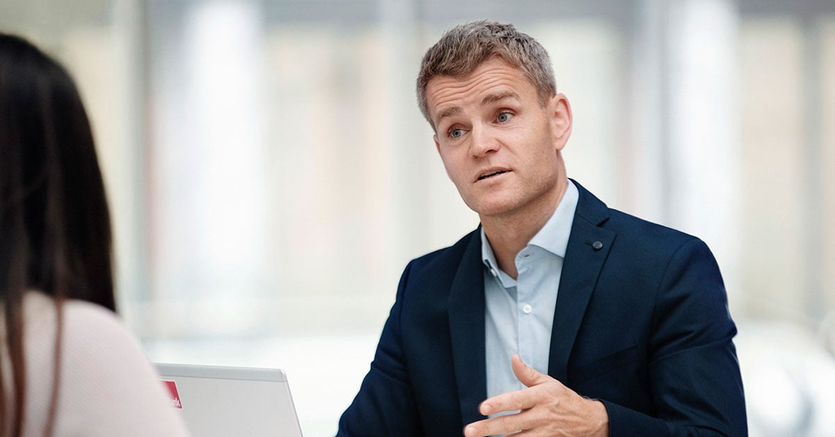 Anders jobber som boliglånsrådgiver i BN Bank og snakker med kunde, til illustrasjon for eiendomsmegler Krogsveen