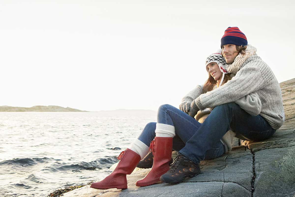 Kvinne lener seg mot mann på svaberg, til illustrasjon for skatt og samboere