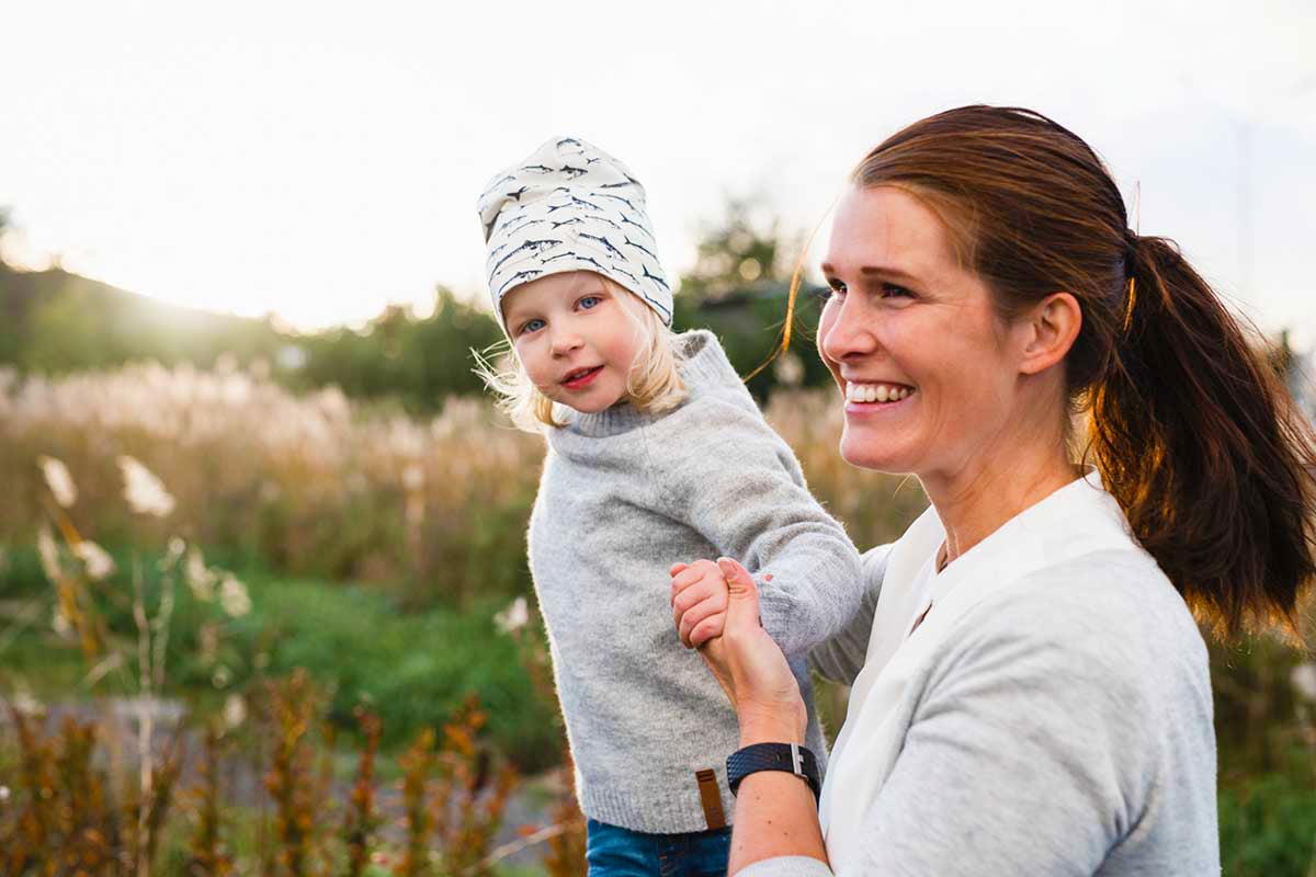 Kvinne og barn leker ute i gresset, til illustrasjon for budsjett til familie