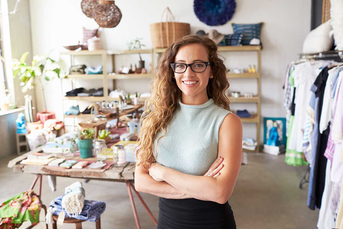 Dame står med armene i kors og viser frem sin butikk, til illustrasjon for selskap under stiftelse